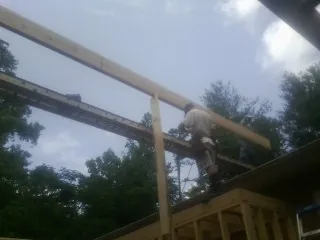 Carpenter setting a ridge beam over a new addition frame — Ice Dam Removal by Roofing Brothers in Meldrim