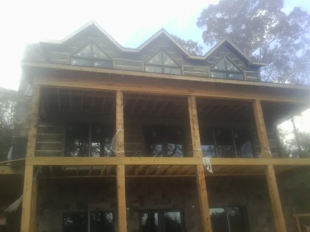 Dormers and porch framing on a large log home under construction — Roof Coating work by our crew in Meldrim