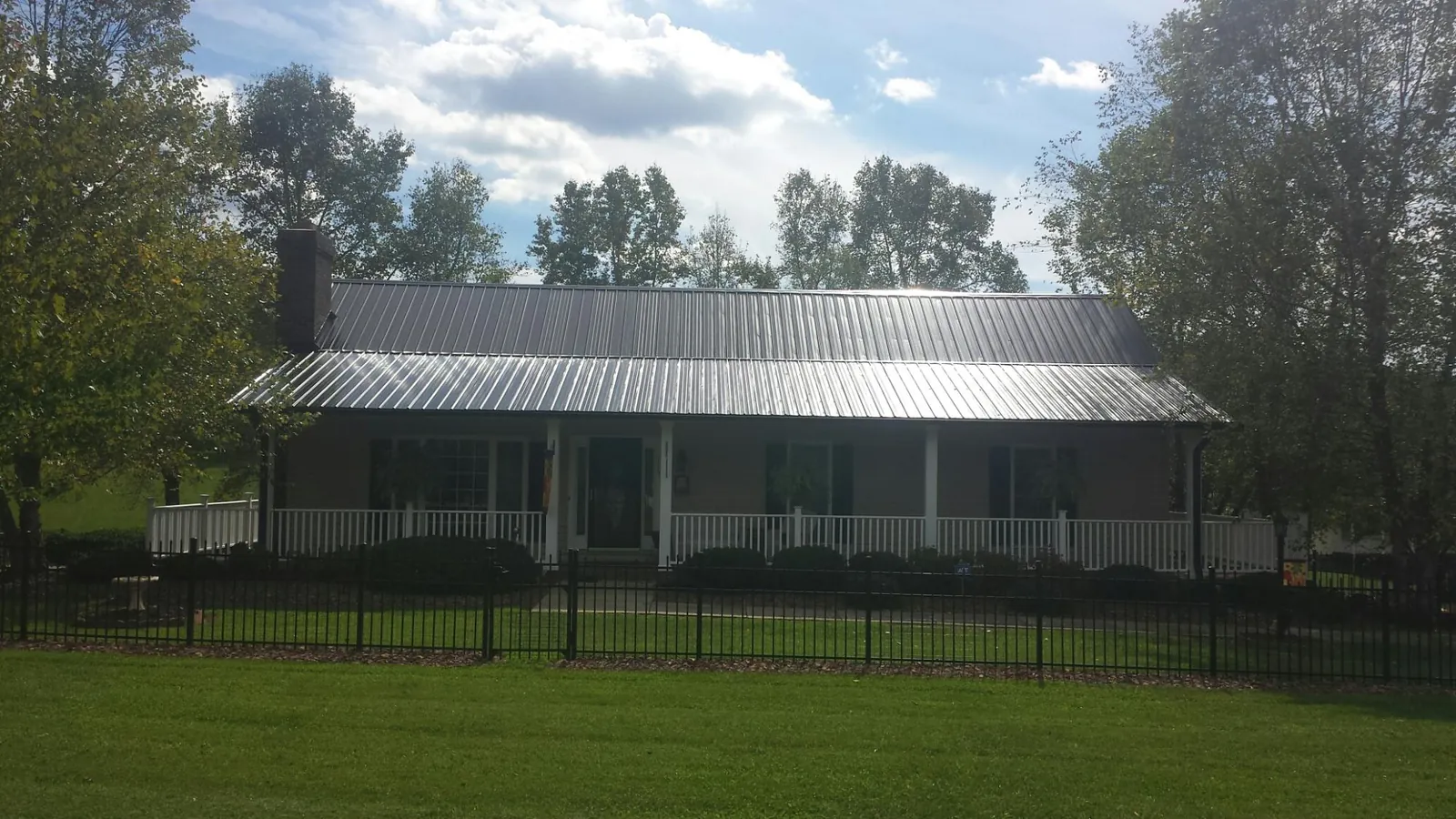 Gray metal roof on a brick ranch with a full width front porch — Gutter Guard Installation work by our crew in Meldrim