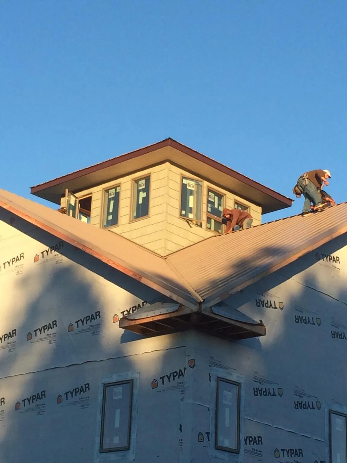 Roofers working around a rooftop cupola on a new metal roof at sunset — Roof Waterproofing in Meldrim by Roofing Brothers